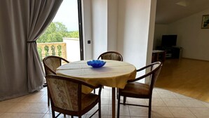 Un coin repas avec une table ronde, quatre chaises, un bol bleu et une fenêtre avec des rideaux.