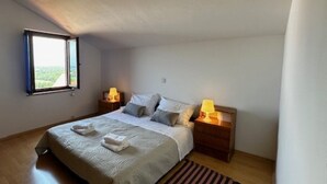 Une chambre à coucher avec un lit, deux tables de chevet avec des lampes, une fenêtre et un tapis à rayures.