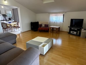 Un salon comprenant un canapé, une table basse, un téléviseur et un coin repas avec des chaises et une table.