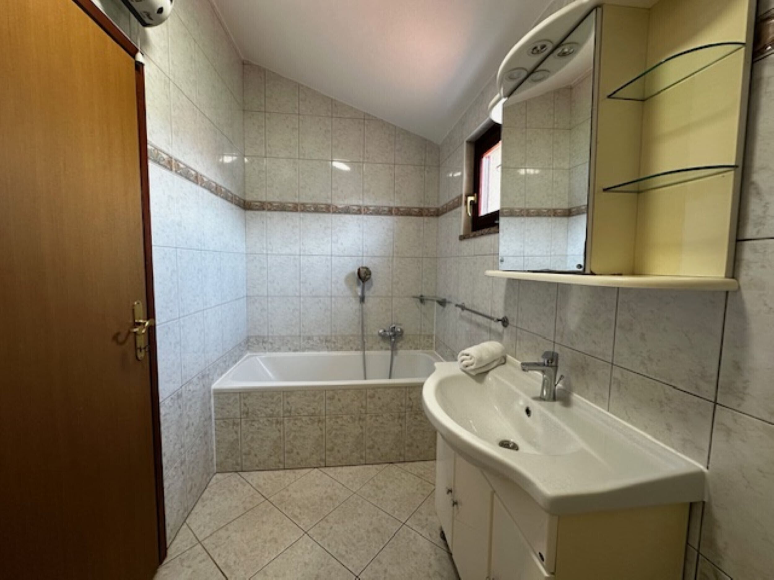 A bathroom with a bathtub, a sink, and a mirror.