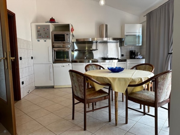 Une cuisine avec une table à manger, des chaises et un saladier bleu.