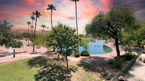 A park with a pond, palm trees, and a sunset sky. - 2BR condo w golf course views, balcony (Mesa)