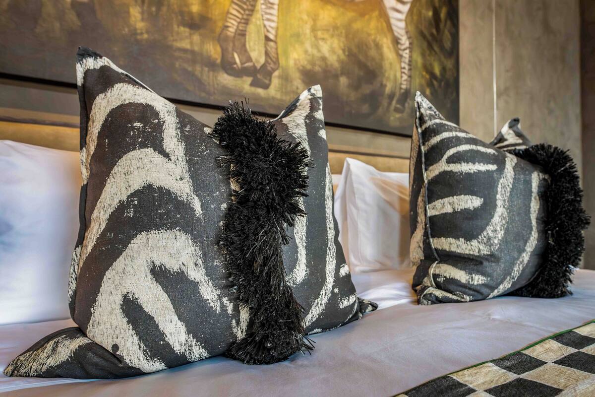A bed with two decorative pillows featuring a zebra pattern and black tassels.