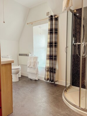 A modern bathroom with a shower, toilet, and sink. - Loch Ness Gate House Apartments (Fort Augustus)