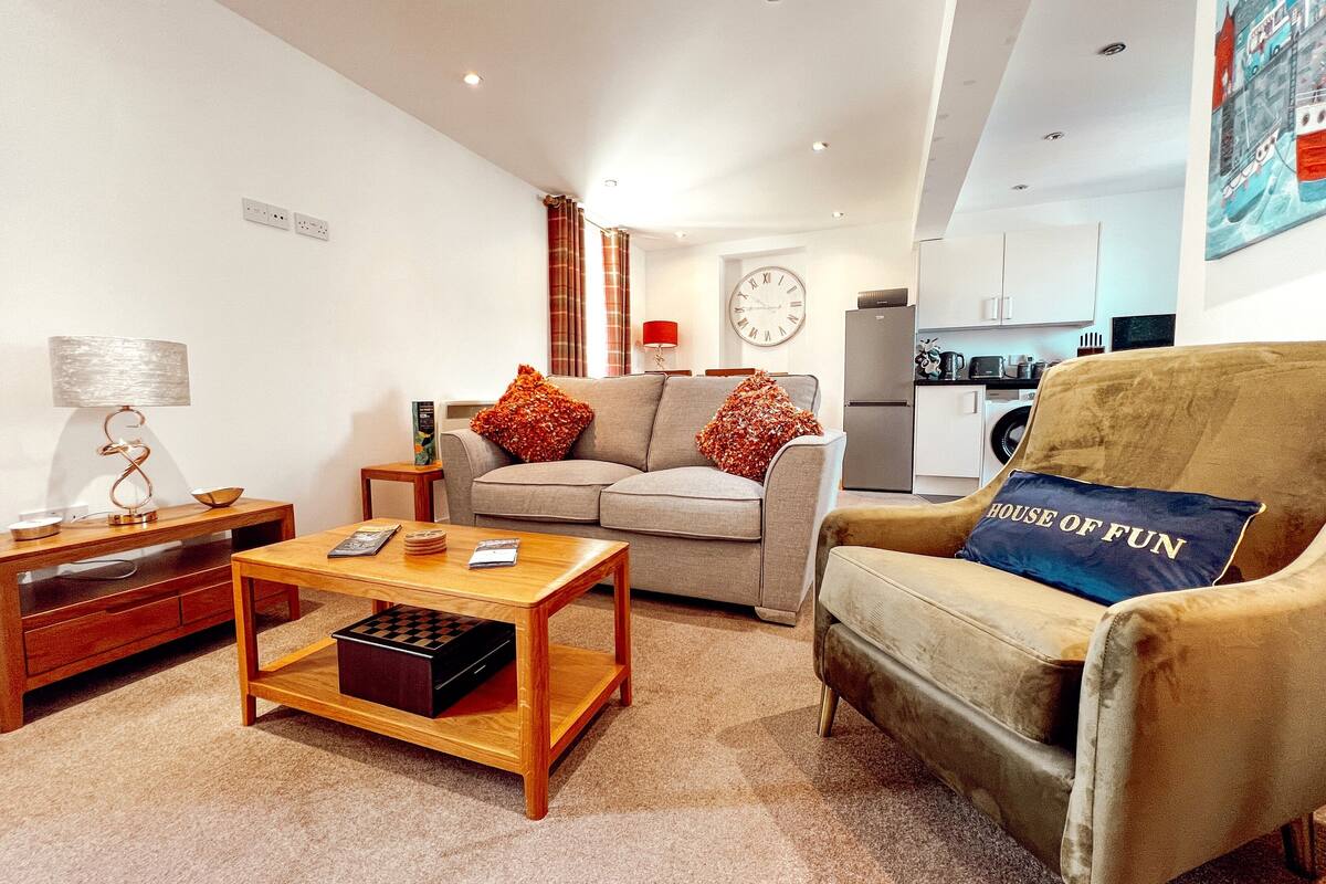A living room with a sofa, armchair, coffee table, and a small side table with a lamp.