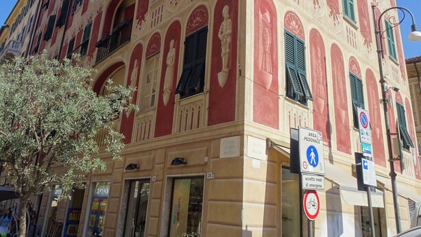 Un edificio de varios pisos con detalles arquitectónicos ornamentales, incluyendo ventanas en arco y molduras decorativas.