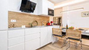 Una cocina moderna con armarios blancos, microondas integrado y televisor de pantalla plana.