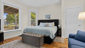 Une chambre avec un grand lit, une fenêtre, une porte et une chaise bleue.