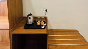 A small wooden table with a kettle, two mugs, and a tray. - Maharishi Inn (Faizabad)