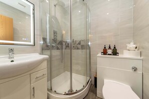 Une salle de bain moderne avec une douche à parois de verre, un lavabo blanc et des toilettes.