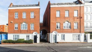 Une rangée d’immeubles en briques rouges, avec des encadrements de fenêtres blancs et une arche centrale.