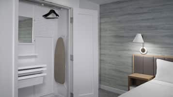A hotel room with a walk-in closet, a bed with a wooden headboard, a bedside table with a lamp, and a wall with a textured pattern.
