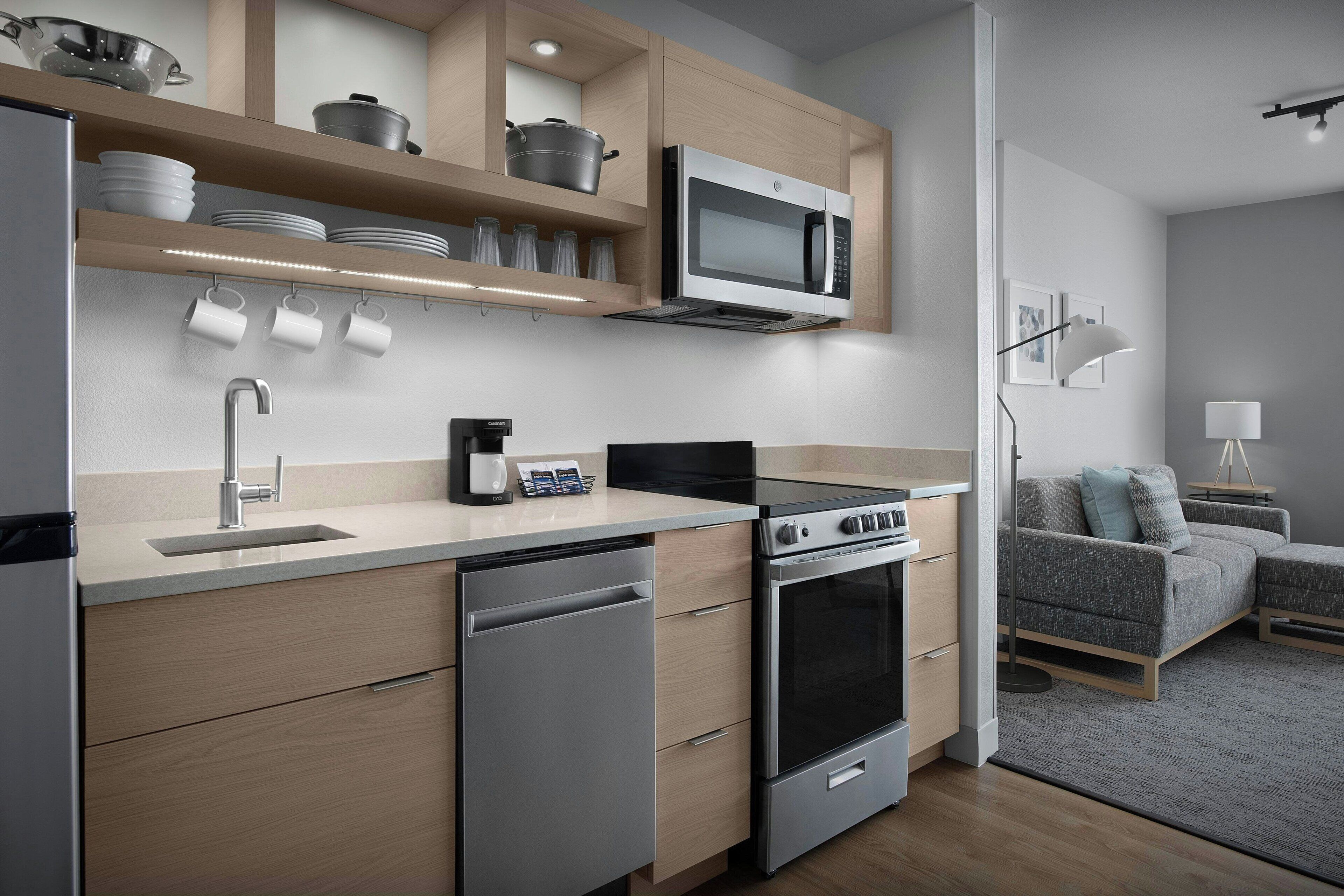 A modern kitchen with built-in appliances, a dishwasher, and a dining area with a sofa and lamp.