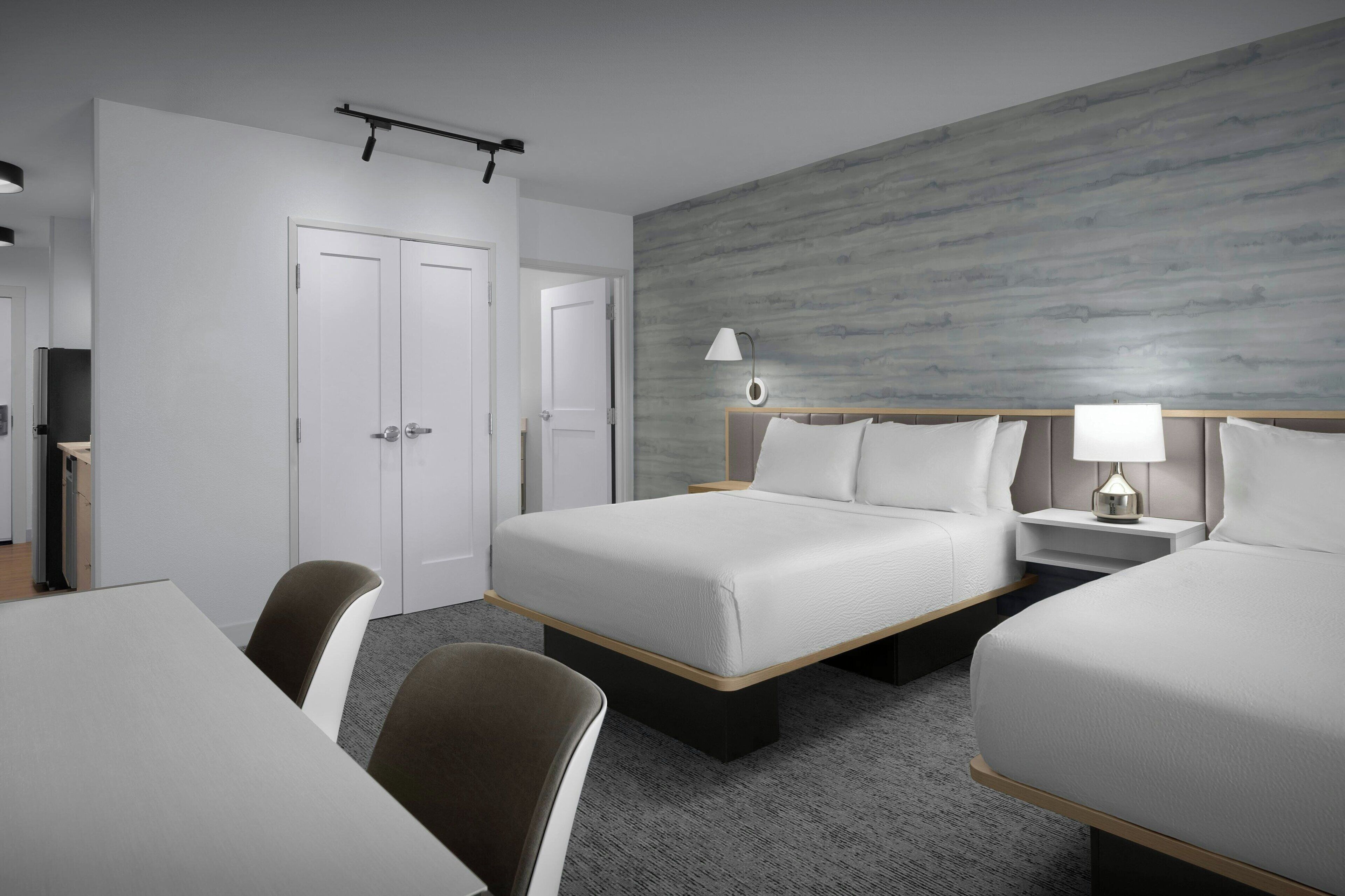 Une chambre d’hôtel avec deux lits, un bureau et une chaise.
