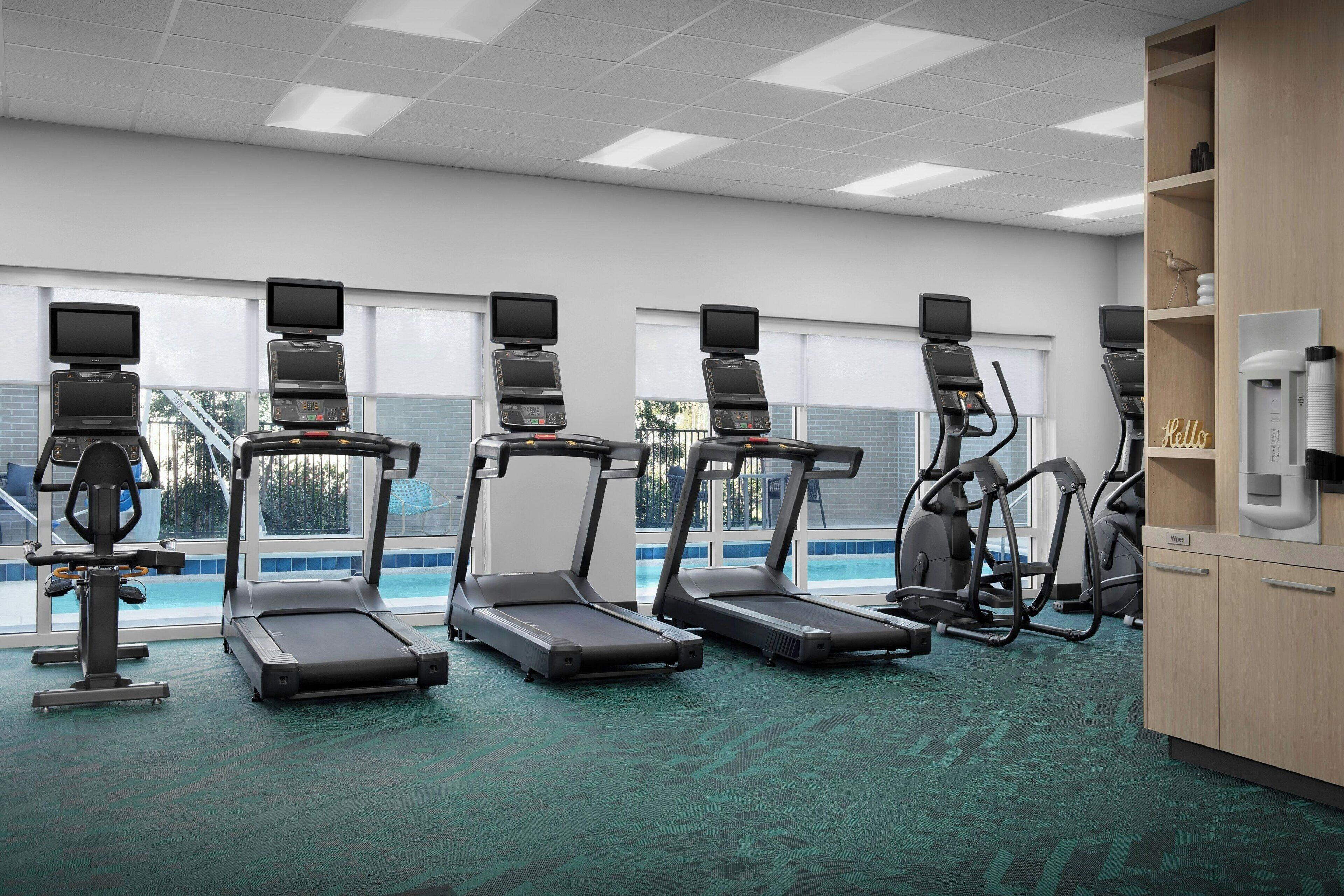 Een fitnessruimte met loopbanden, elliptische trainers en een waterfontein.
