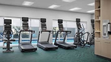 A gym with treadmills, elliptical machines, and a water fountain.