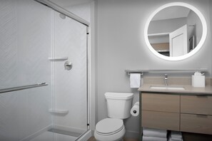 Ein modernes Badezimmer mit Duschkabine aus Glas, Toilette, Waschbecken mit Spiegel und Holzschränken.