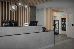 En moderne receptionsdisk med to computerarbejdspladser, en automt og en væg med lodrette trælameller.