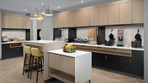 Una cocina moderna con armarios de madera, encimera blanca y una cesta de frutas.