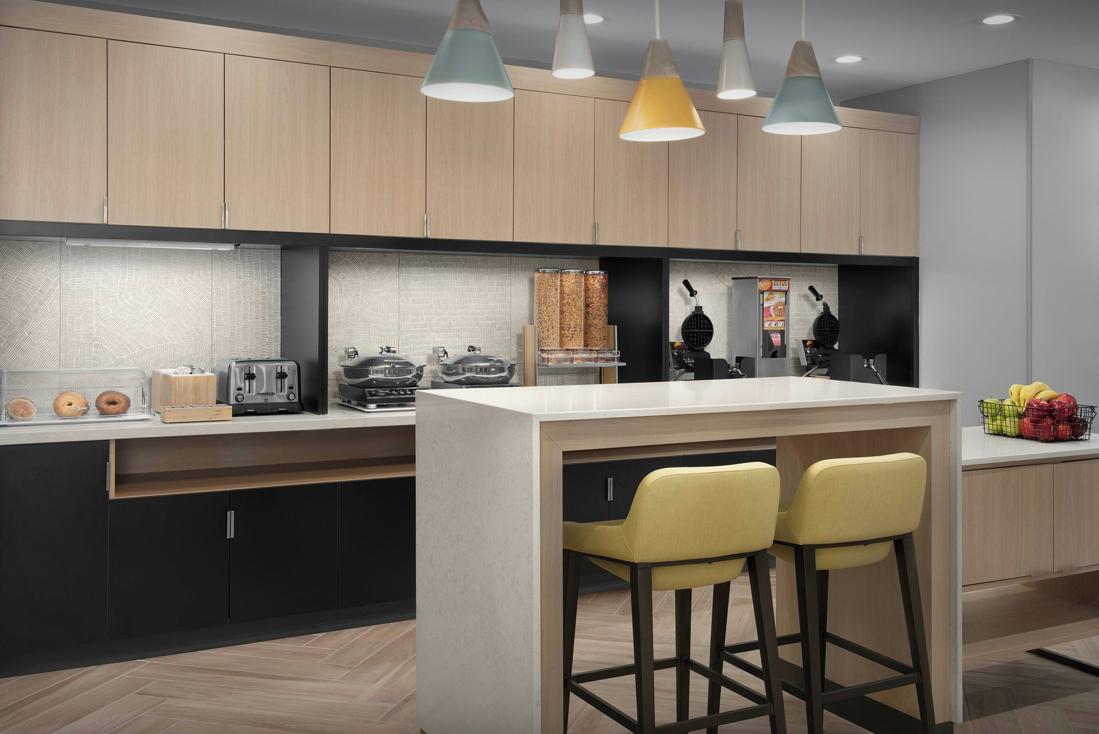 A modern kitchen with wooden cabinets, a central island with bar stools, and pendant lighting.