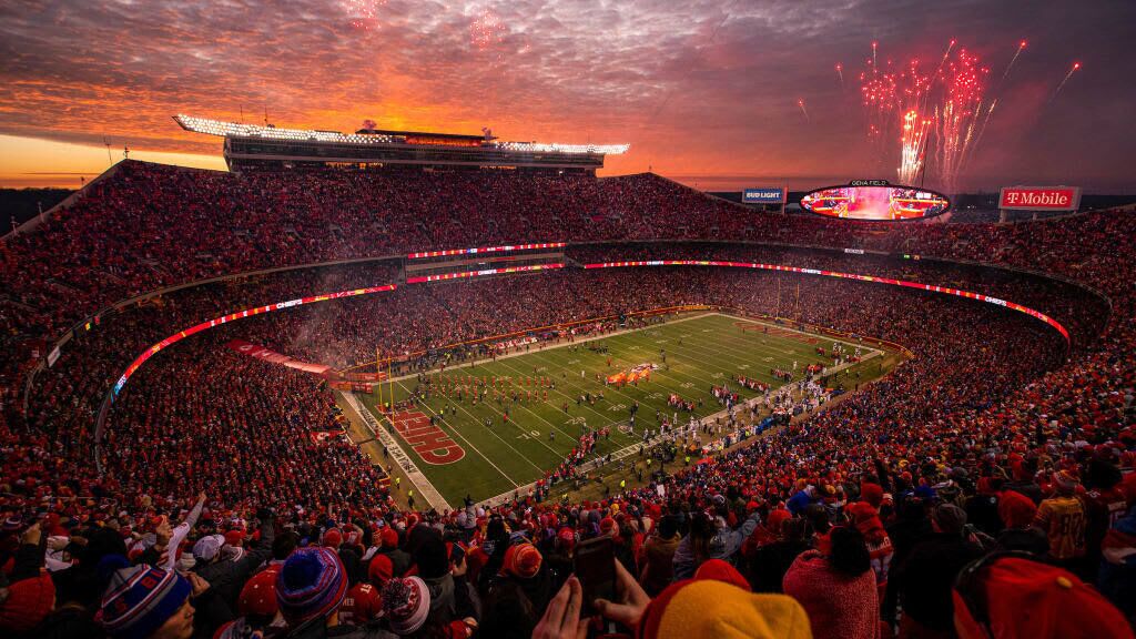 A stadium filled with spectators, a football field, and a large scoreboard.
