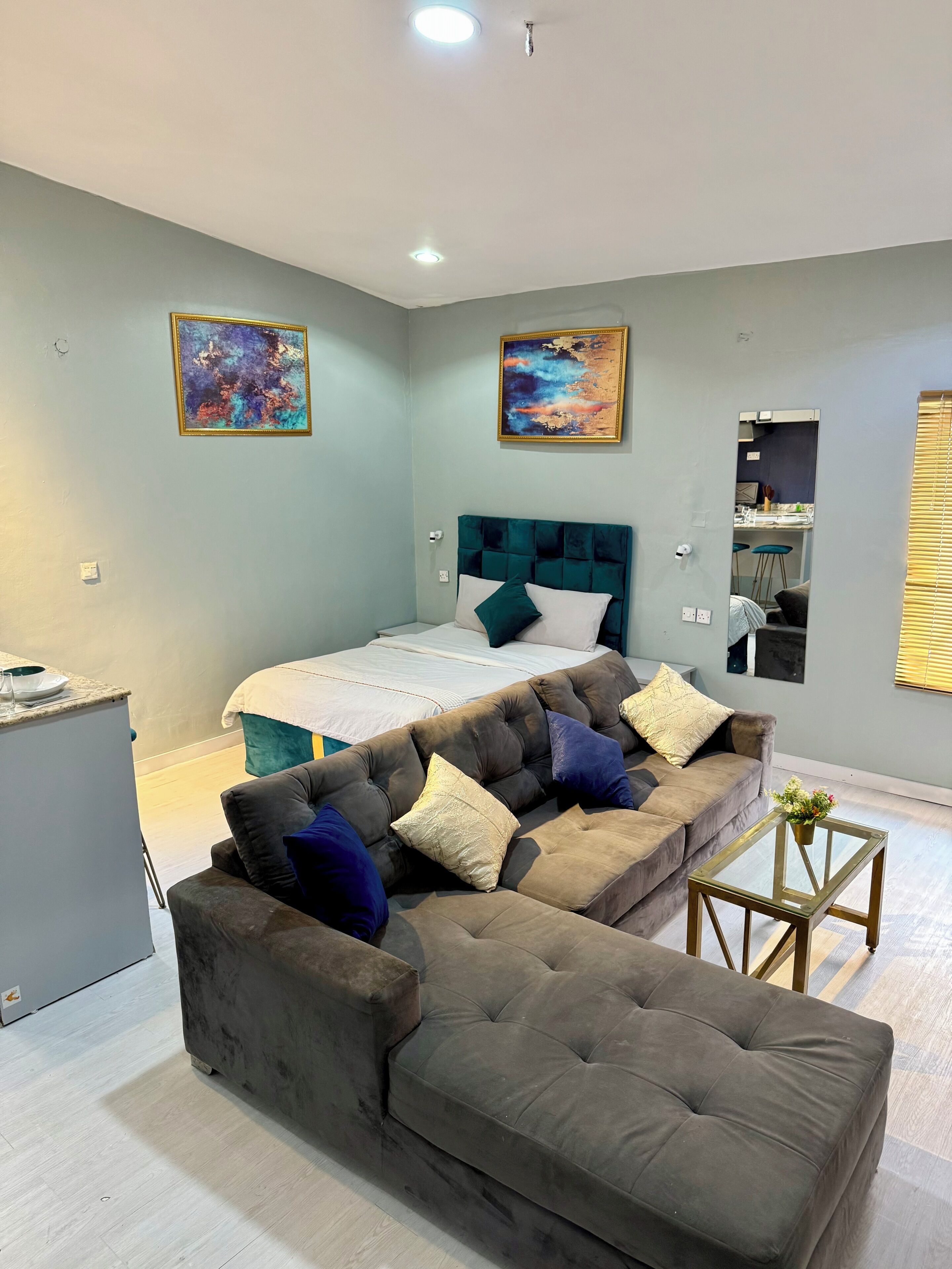 Un dormitorio moderno con cama, sofá, una mesita de centro y obras de arte en las paredes.