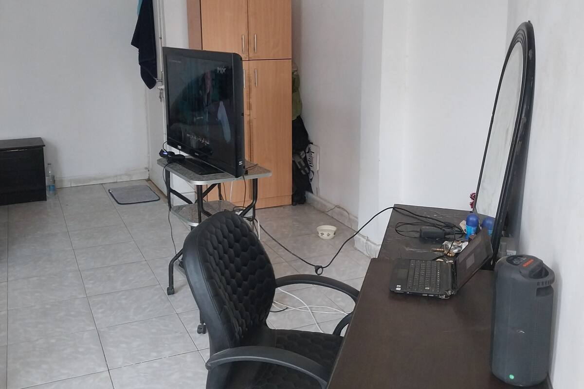Un pequeño espacio de oficina con escritorio, silla, computadora y televisor.
