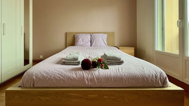 A neatly made bed with a wooden headboard, a nightstand, and a window with a view of the outside.