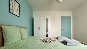 A bedroom with a bed, a wardrobe, a door, and a framed picture on the wall.