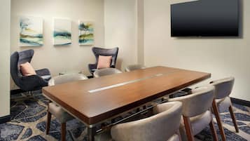 A conference room with a wooden table, six chairs, and three abstract paintings on the wall.