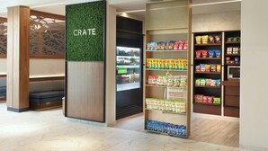 Ein Geschäft mit dem Schriftzug 'CRATE', Regalen voller Snacks und einer Sitzgelegenheit.