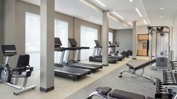 Uma academia moderna com esteiras, elípticos e equipamentos de musculação.