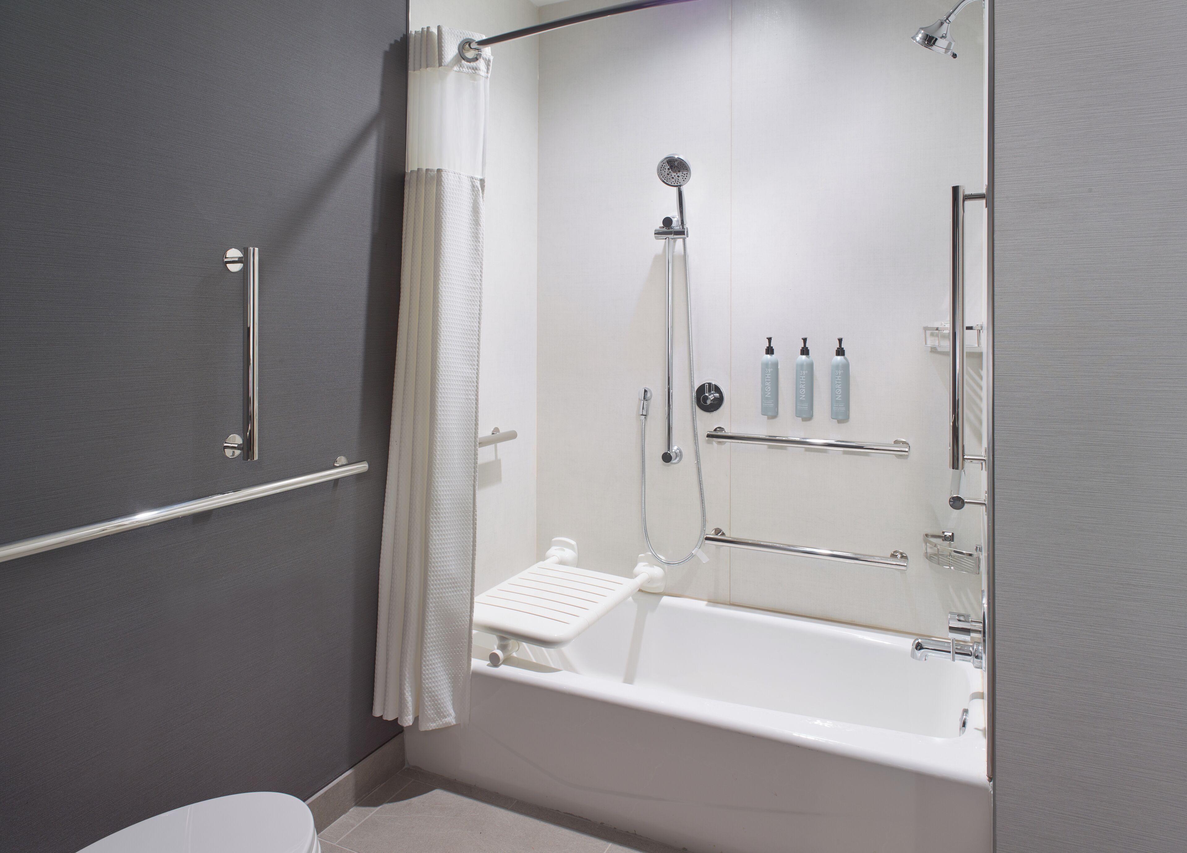 A modern bathroom with a bathtub, shower, and toilet.