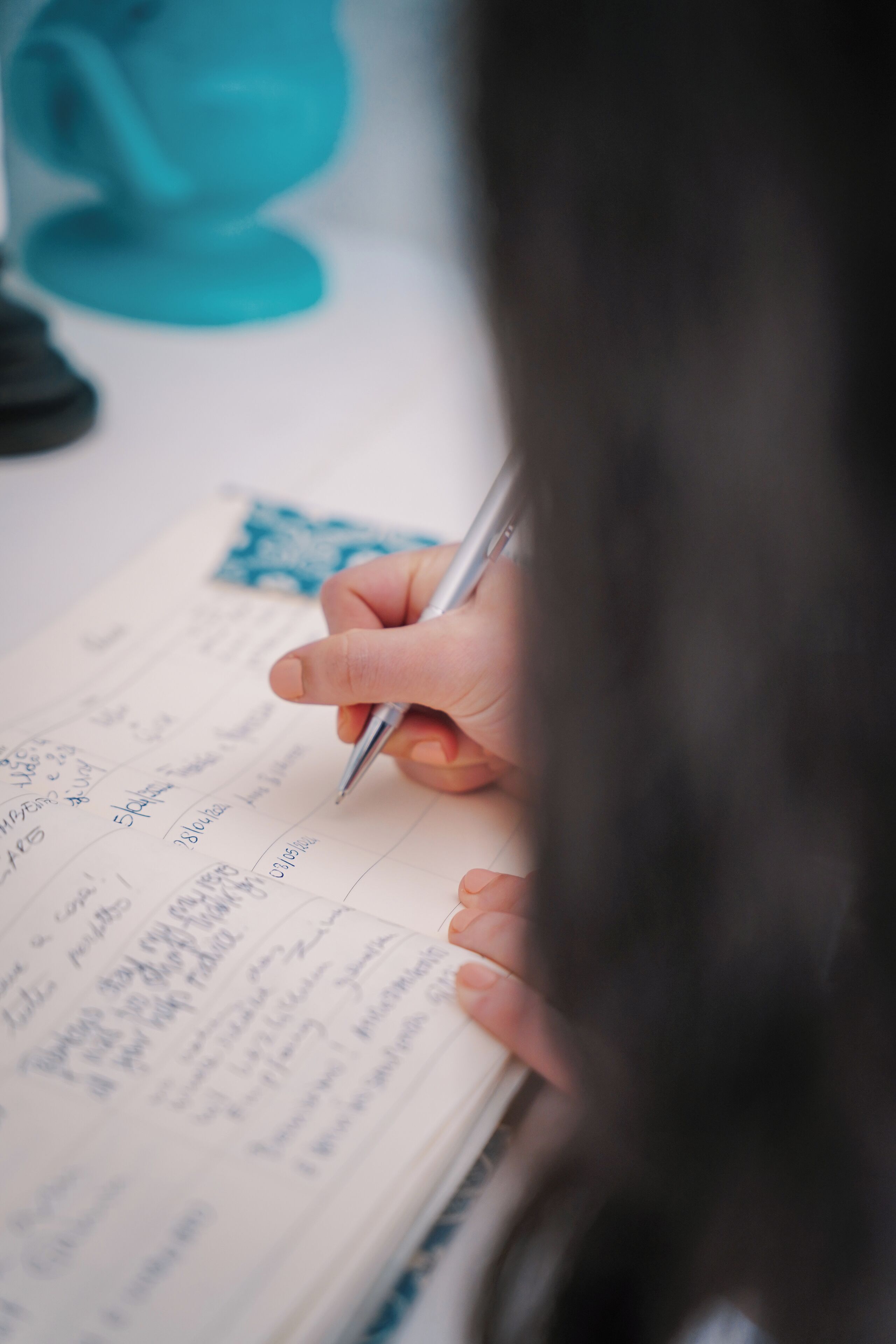 A hand writing on a notepad with a pen.