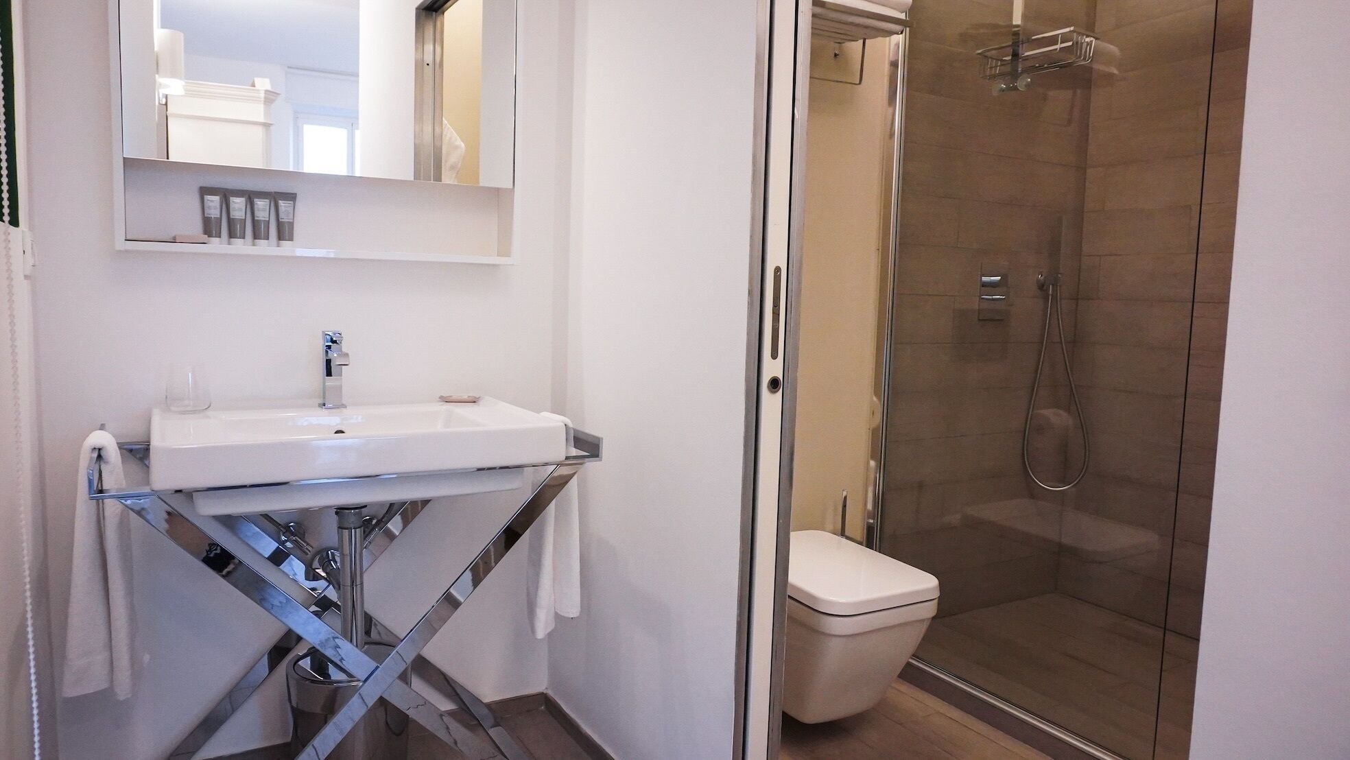 A modern bathroom with a glass shower enclosure, a white sink with a chrome faucet, and a toilet.