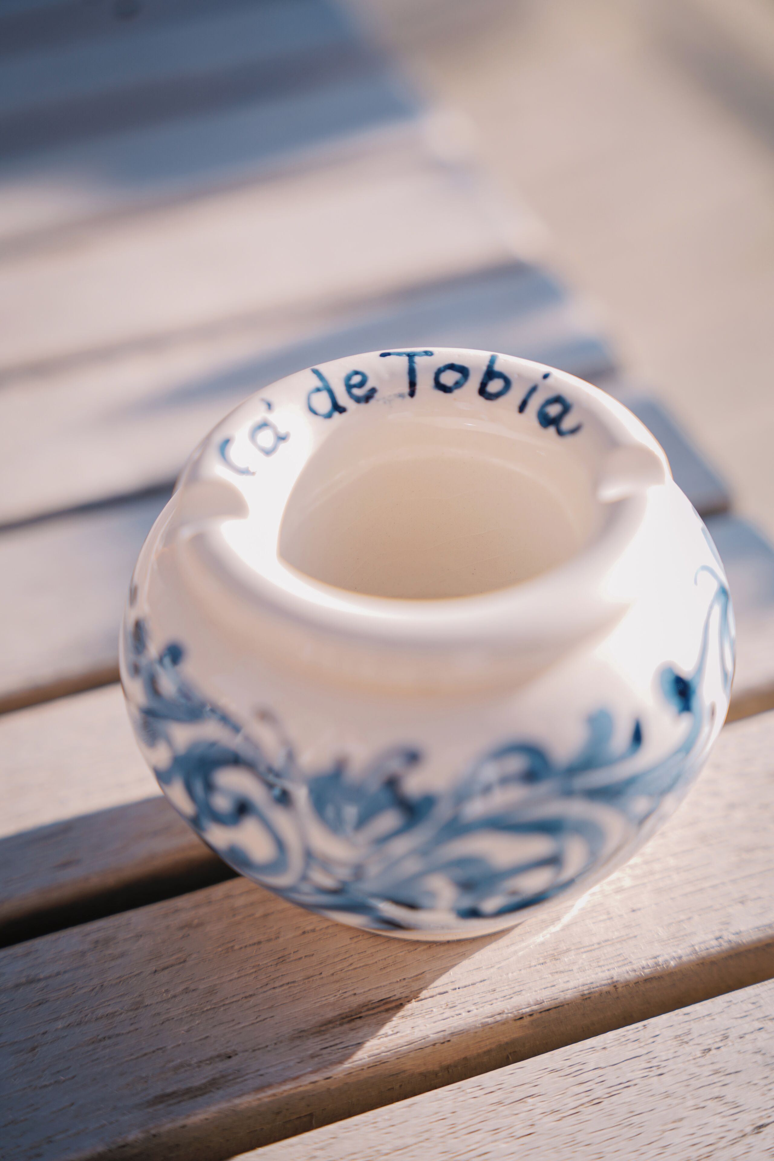 Uma tigela de cerâmica com a inscrição 'Café de Tobias' sobre uma superfície de madeira.
