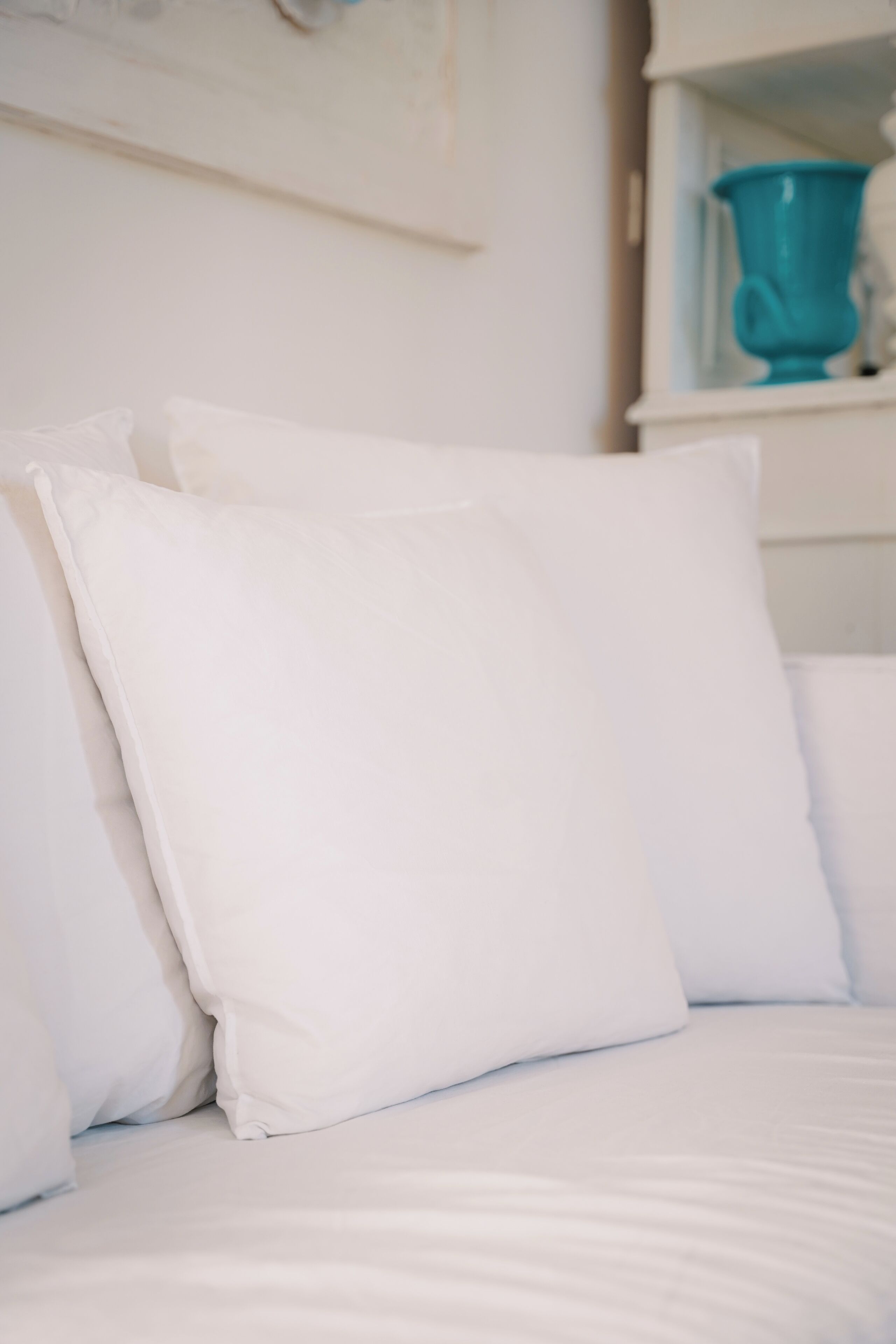 Un letto con biancheria e cuscini bianchi.