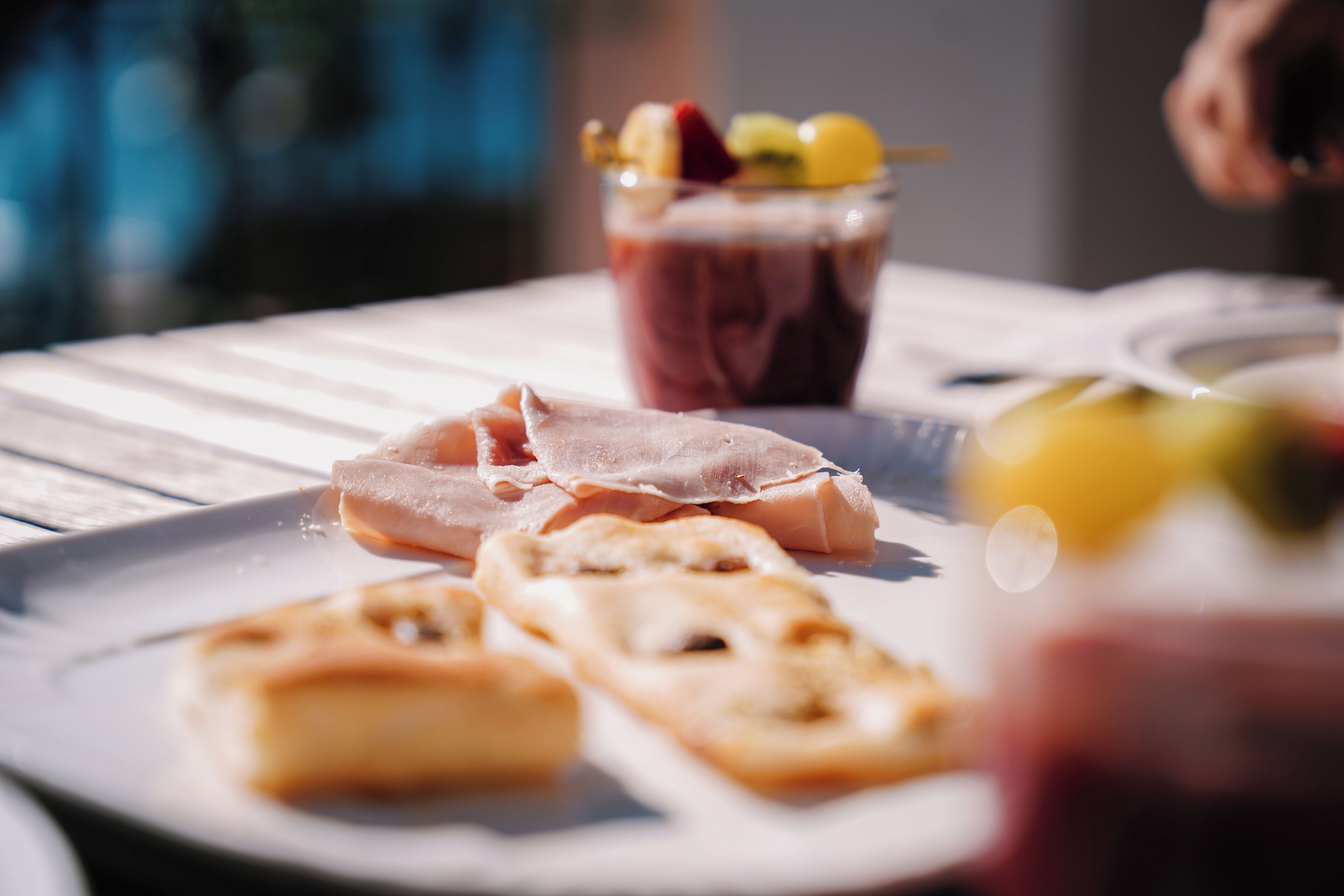 A plate with slices of ham and a glass of fruit juice.
