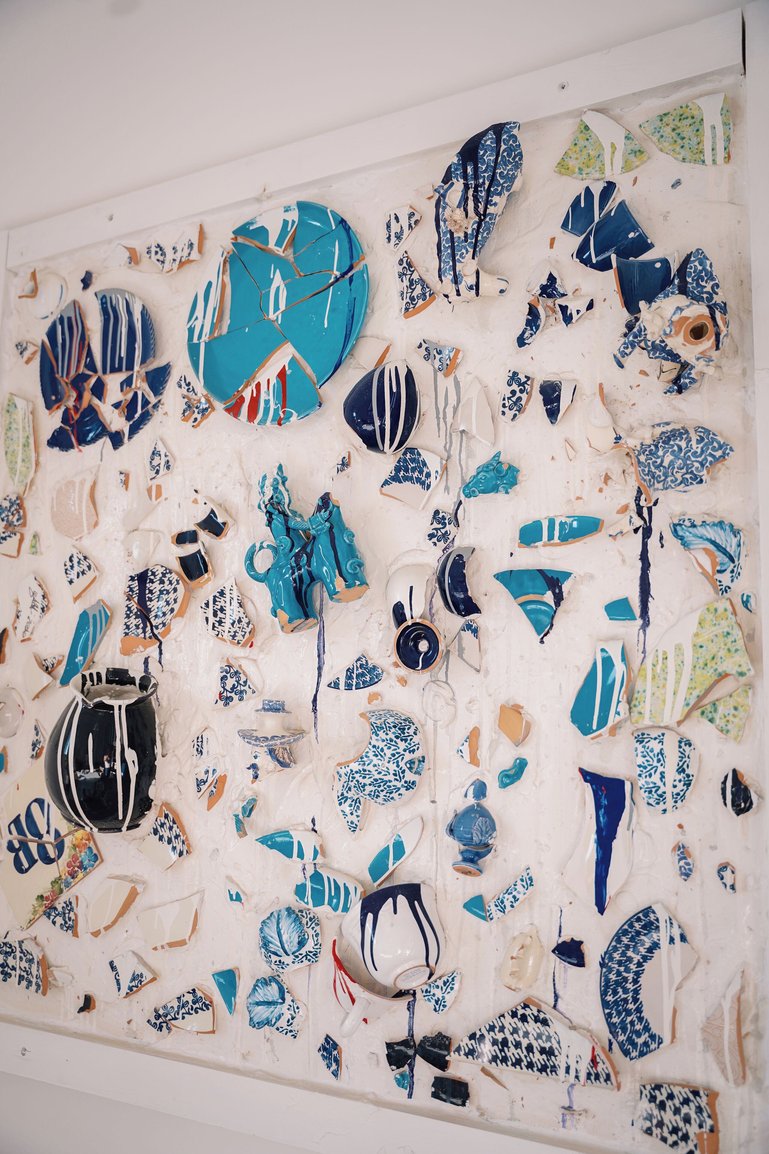 Un mur recouvert de divers éléments et fragments en céramique.