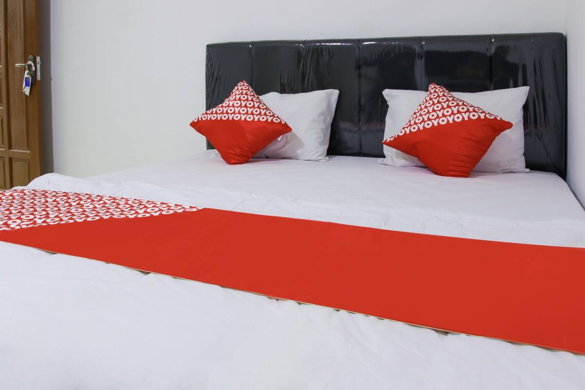 A bed with a red and white bedspread, two red pillows with white text, and a dark headboard.