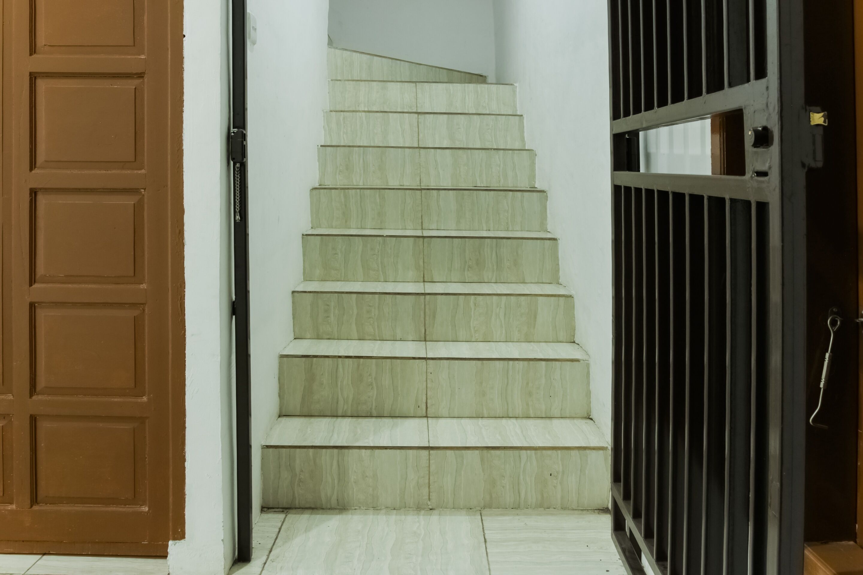 A wooden staircase leading to a door with a metal gate.