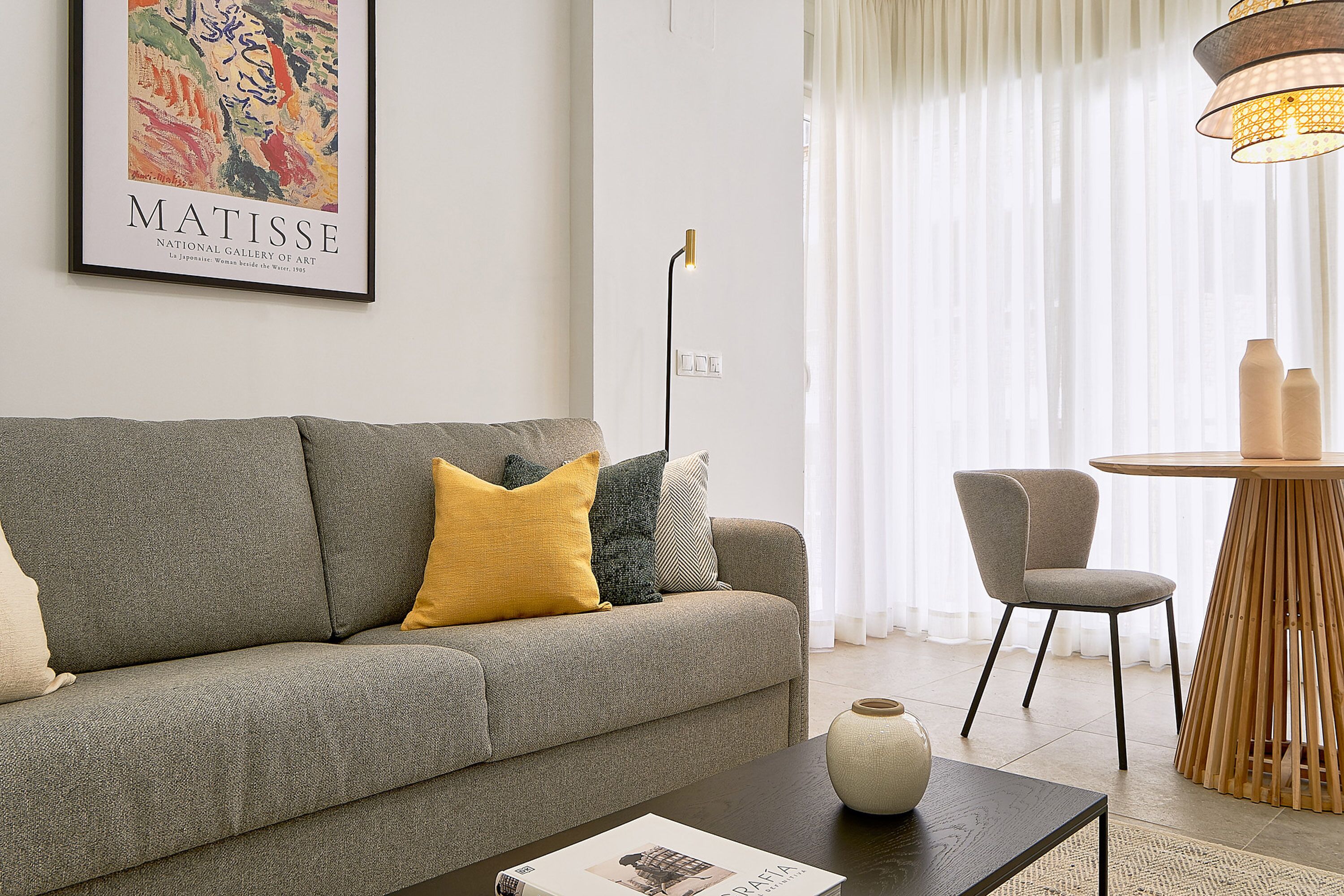 A living room with a grey sofa, a coffee table, a chair, and a table lamp.