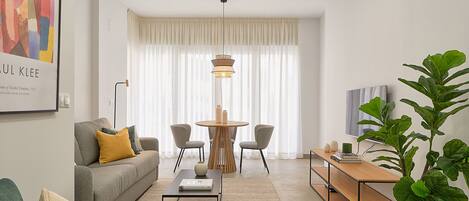 Una sala de estar moderna con un sofá, una mesa de centro y una zona de comedor con sillas y una mesa.