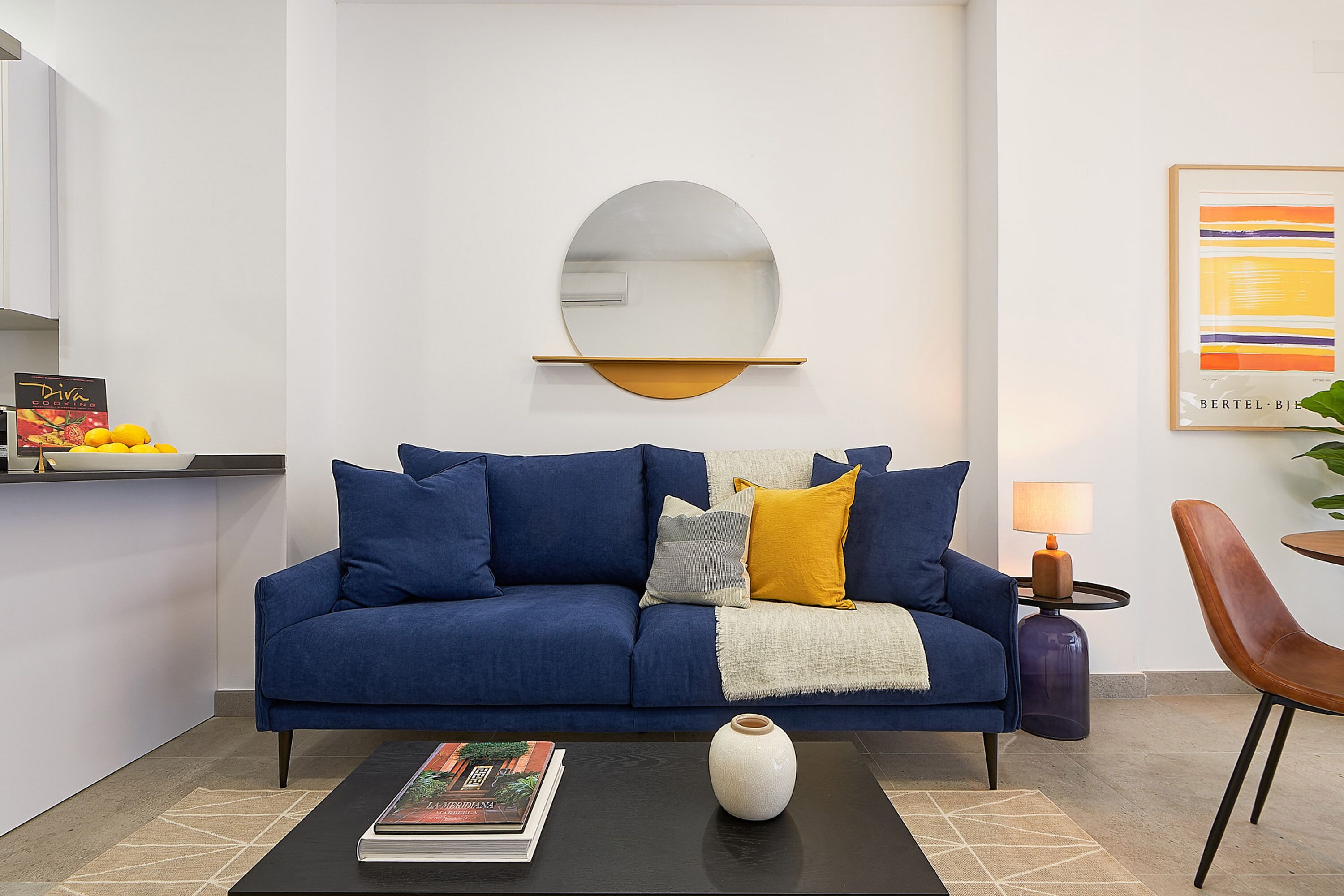 A modern living room with a blue sofa, a white vase, and a magazine on a coffee table.