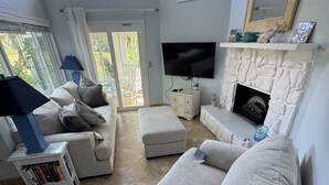 A living room with a stone fireplace, a flat-screen TV, and a sofa.