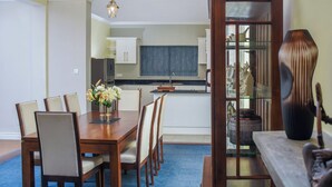 Un comedor con una mesa y sillas de madera, un jarrón de flores y un aparador con objetos decorativos.