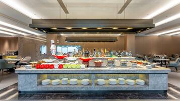 Una presentación de buffet moderna con diversos alimentos y bebidas, una encimera de mármol impecable y un diseño interior contemporáneo.