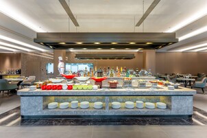 Una presentación de buffet moderna con diversos alimentos y bebidas, una encimera de mármol impecable y un diseño interior contemporáneo.