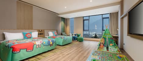 Habitación de hotel moderna con una cama grande, un sofá, un espacio de juegos y vistas a la ciudad.