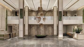 Un vestíbulo moderno con un mostrador de recepción central, zonas de estar y elementos decorativos como una gran jardinera y arte abstracto en la pared.